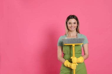 Pembe arka planda sarı süpürgesi olan genç kadın, mesaj için boşluk