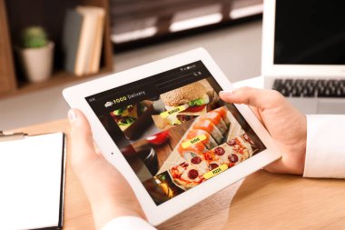 İnternetten yemek sipariş etmek için tablet kullanan bir adam, yakın plan. Teslimat hizmeti kavramı