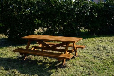 Güneşli bir günde parkta bankları olan boş ahşap piknik masası.