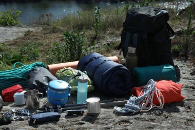 Backpack with hiking equipment on rock near river