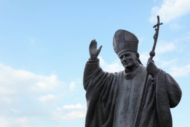 LVIV, UKRAINE - MAYIS, 04, 2022: Papa II. John Paul 'un heykeli bulutlu gökyüzüne karşı, metin için boşluk