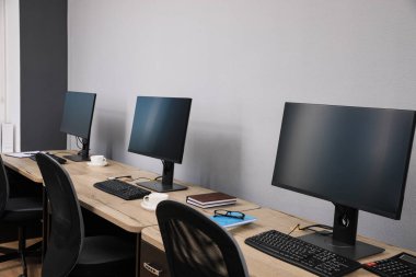 Ofisin içini aç. Açık gri duvarın yanında bilgisayarları olan modern işyerleri