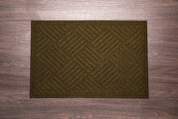 Stylish door mat on wooden floor, top view