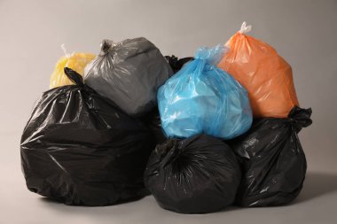 Trash bags full of garbage on grey background