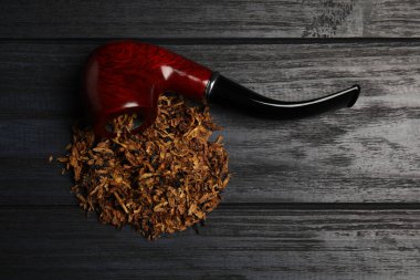 Sigara piposu ve kuru tütün siyah ahşap masada, düz yatıyordu.