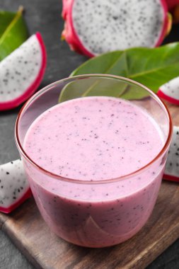 Lezzetli pitahaya smoothie ve siyah masada taze meyveler, yakın plan.