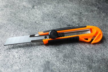 Gri masadaki turuncu alet bıçağı. Yapı aracı