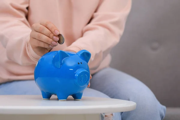 Young Woman Putting Coin Piggy Bank Table Indoors Closeup — Photo