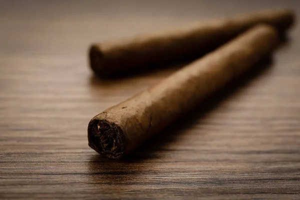タバコの葉に包まれた葉巻は 木製のテーブルの上に閉じられます — ストック写真