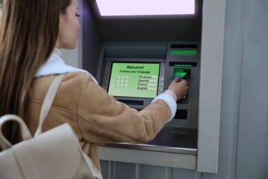 Dışarıda para çekmek için para makinesini kullanan genç bir kadın.