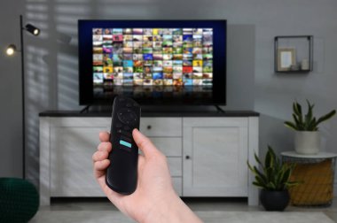 Uzaktan kumandalı kadın evde televizyon izlerken kanal değiştiriyor, kapatıyor