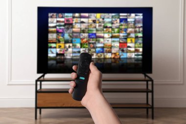 Uzaktan kumandalı kadın evde televizyon izlerken kanal değiştiriyor, kapatıyor