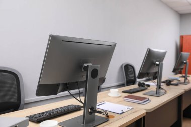 Ofisin içini aç. Açık gri duvarın yanında bilgisayarları olan modern işyerleri