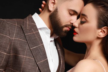 Siyah arka planda seksi bayan olan yakışıklı sakallı adam, yakın plan.