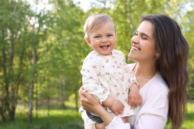 Güneşli bir günde parkta sevimli bebeğiyle mutlu bir anne. Mesaj atmak için uygun bir yer.