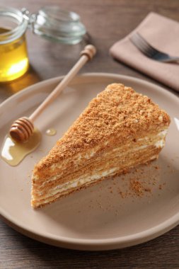 Ahşap masada servis edilen lezzetli katmanlı ballı kek dilimi.