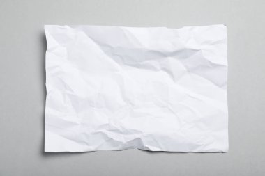 Gri arkaplan üzerine beyaz buruşuk kağıt yaprağı, üst görünüm