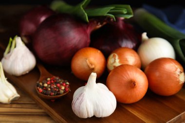 Taze soğan soğanları, pırasa, sarımsak ve biberler ahşap masada, yakın plan.