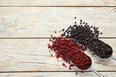 Beyaz ahşap masada kurutulmuş siyah ve kırmızı üzümlü üzümler, düz. Metin için boşluk