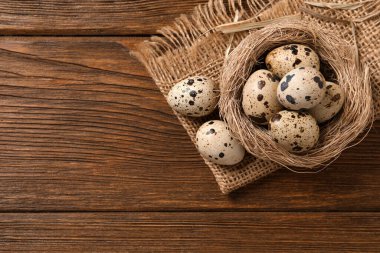Yuva ve bıldırcın yumurtaları ahşap masada, düz yerde. Metin için boşluk