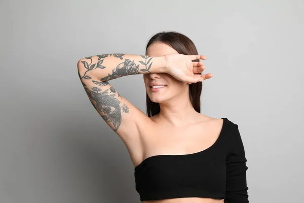 Gri Arka Planda Kollarında Dövmeleri Olan Güzel Bir Kadın — Stok fotoğraf
