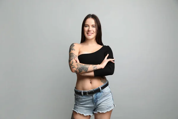 Vacker Kvinna Med Tatueringar Kroppen Mot Grå Bakgrund — Stockfoto
