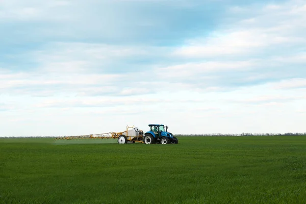 春の日に畑で農薬を散布するトラクター — ストック写真