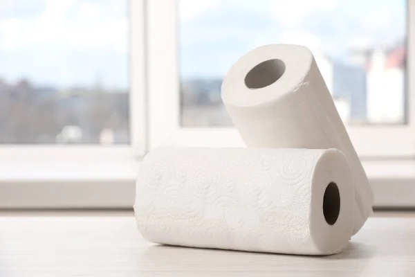 Rolls of paper towels on white wooden table indoors. Space for text