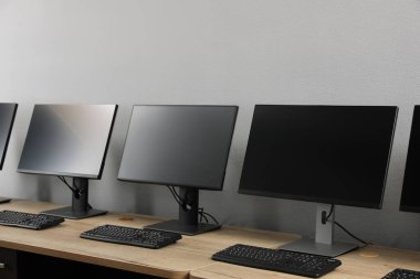 Ofisin içini aç. Açık gri duvarın yanında bilgisayarları olan modern işyerleri