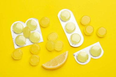 Sarı arka planda bir sürü limonlu öksürük pastili var.