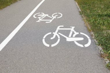 Kaldırımın kenarına asfalt boyanmış beyaz tabelası olan bisiklet yolu