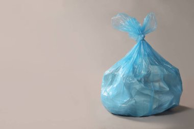 Gri arka planda çöp dolu bir çöp torbası. Metin için boşluk