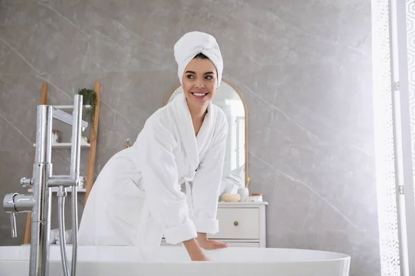 漂亮的年轻女人穿着柔软的白色长袍在家里的浴缸边 — 图库照片