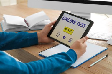 İçerideki masadaki tablette çevrimiçi teste giren adam, yakın plan.