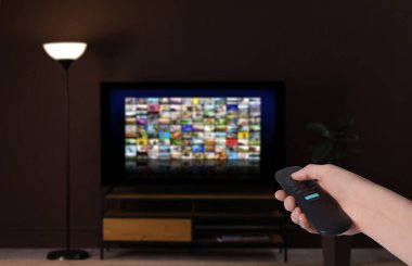 Uzaktan kumandalı kadın evde televizyon izlerken kanal değiştiriyor, kapatıyor