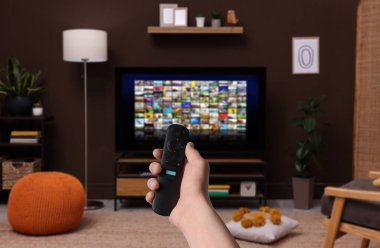 Uzaktan kumandalı kadın evde televizyon izlerken kanal değiştiriyor, kapatıyor