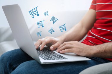 Evdeki online alışveriş için dizüstü bilgisayar kullanan bir adam.