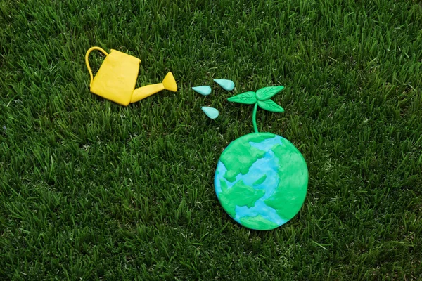 地球日快乐 用塑料行星和浇灌罐在绿草上构成平坦的地面 — 图库照片