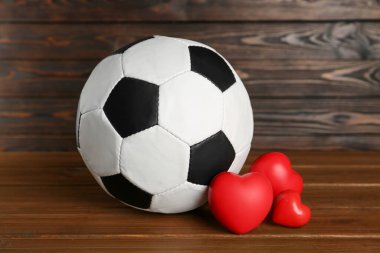Futbol topu ve kalpler tahta masada.