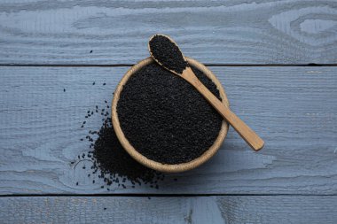 Açık gri ahşap masada siyah susamlı kâse ve kaşık, düz yatıyordu.