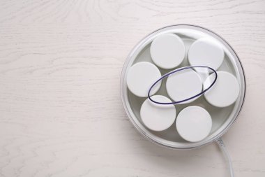 Beyaz ahşap masasında kavanozları olan modern yoğurt imalatçısı. Metin için boşluk