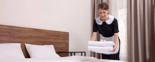 漂亮的女服务员把新鲜的毛巾放在旅馆房间的床上 条幅设计 — 图库照片
