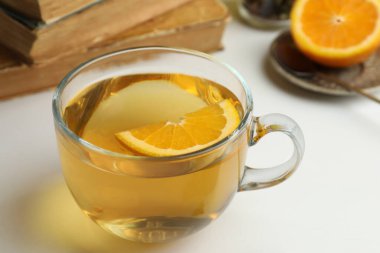 Bir bardak taze demlenmiş çay, portakallı, ışık masasında, yakın plan.