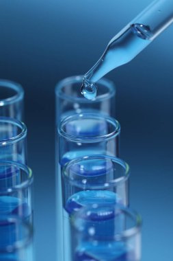 Açık mavi arka planda test tüpüne reaktör damlatılıyor, yakın plan. Laboratuvar analizi