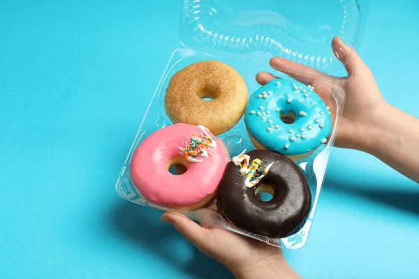 stock image Woman with box of delicious donuts on light blue background, closeup