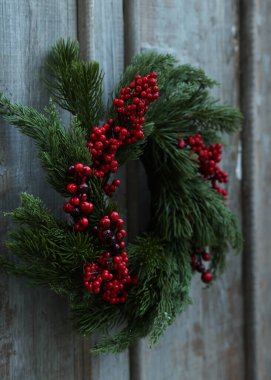 Ahşap duvarda kırmızı böğürtlenli güzel Noel çelengi