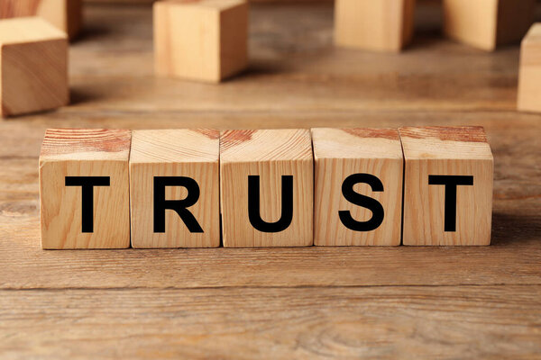 Cubes with word TRUST on wooden table