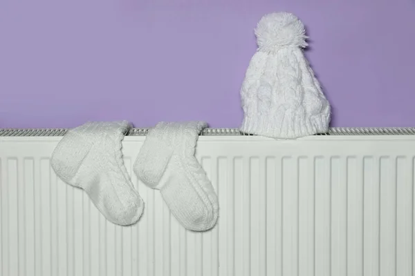 Gestrickte Socken Und Mütze Auf Heizkörper Der Nähe Violette Wand — Stockfoto