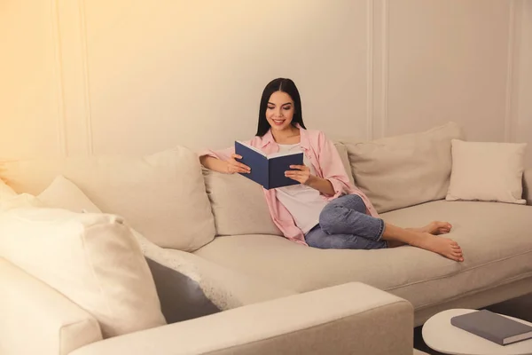 在客厅沙发上看书的女人 — 图库照片