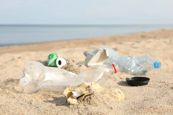 Garbage scattered on beach near sea, closeup. Recycling problem